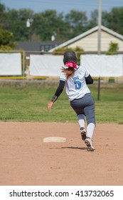 High school softball player stealing a base.