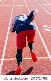 A High School Sprinter Is Practicing The Start Of His Race In The Winter On A Track. Picture Taken From Behind The Athlete.