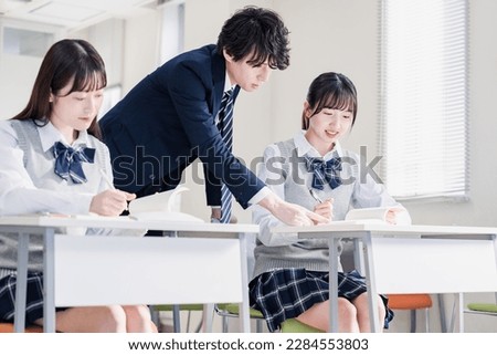High school student asking a question to her teacher in the classroom