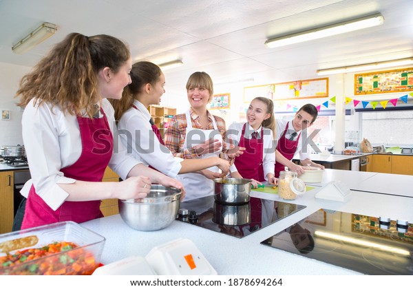 High school student cooking during a home\
economics class with their\
teacher.