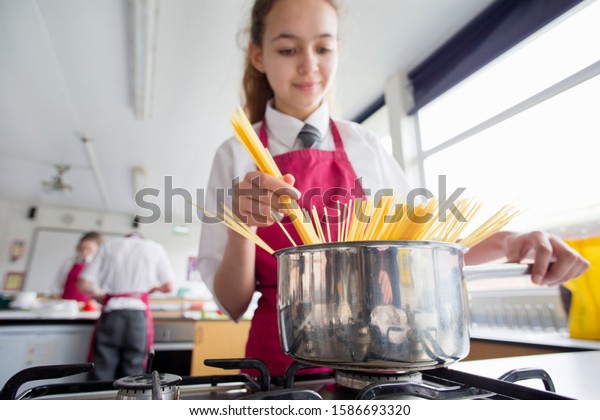 High\
school student cooking pasta in home economics\
class