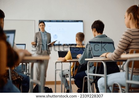 High school student and his classmates learning computer coding on a laptops in the classroom.