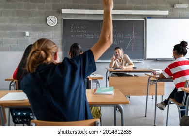 High school student raises hand to ask question. Mature white man teacher grants permission to talk. Multiracial group of students. education concept.