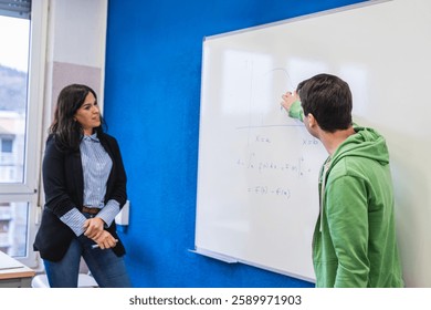 High school student solving a math equation on the whiteboard while the teacher watches during a class