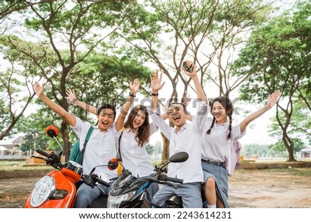 high school students celebrating graduation while sitting on a motorbike