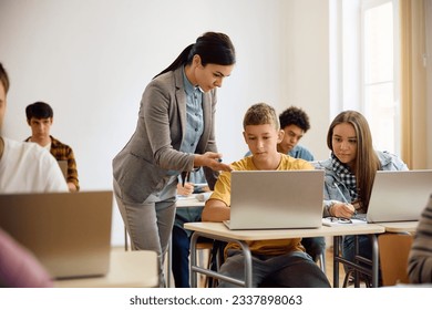 High school students e-learning on laptop with teacher's assistance during computer class in the classroom. 