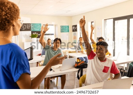 In high school, students raising hands and engaging with teacher in classroom. Education, back to high school, engagement, interaction, learning, studying