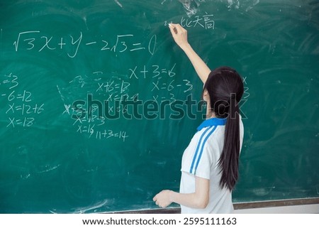 High school students solving math problems on the blackboard in classroom during class