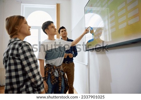 High school students and their teacher using interactive whiteboard during a class.