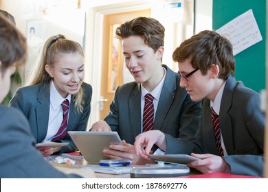 High School Students Using A Digital Tablet And Having A Discussion In The Classroom.