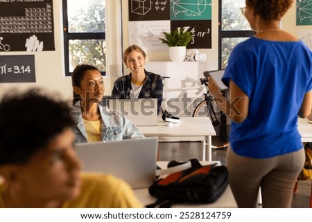 In high school, students using laptops and listening to teacher in classroom. Education, teaching, technology, learning, academic, interaction