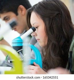 High School Students. Young Pretty Girl Student Peering Through Microscope In Science Classroom