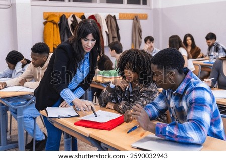 High school teacher explaining lesson to two multi ethnic students sitting at desk, helping them with their homework