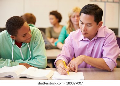 High School Teacher Helping Student With Written Work