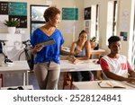 In high school, teacher using tablet while engaging with students in classroom. Education, technology, learning, interaction, digital, instructing