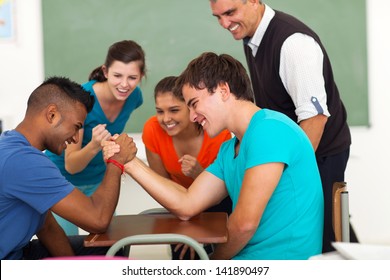 High School Teenage Boys Arm Wrestling In Classroom