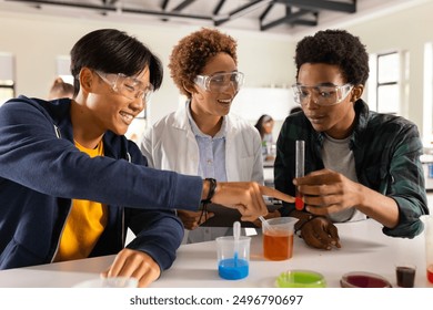 In high school, teenagers conducting science experiment with test tubes in classroom. Education, learning, chemistry, students, laboratory, collaboration - Powered by Shutterstock