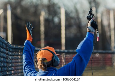 A High School Track And Field Official Raises His Pistol In The Air To Start A Race. 