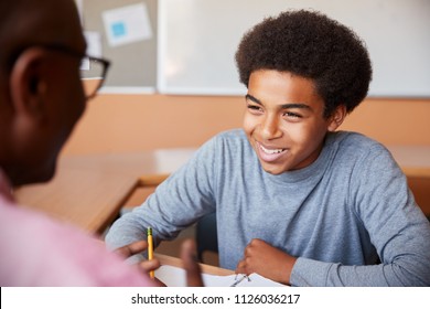 High School Tutor Giving Male Student One To One Tuition At Desk