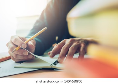 high school or university student holding pencil writing on paper answer sheet.sitting on lecture chair taking final exam attending in examination room or classroom.student in uniform 