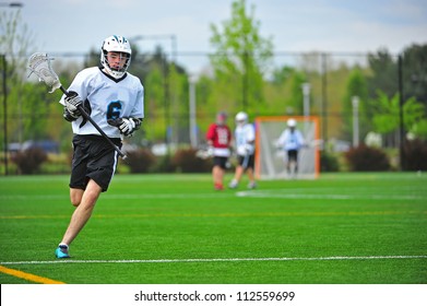 High School Varsity Boys Lacrosse Player In His Protective Gear On The Move Down The Field While Playing A Game