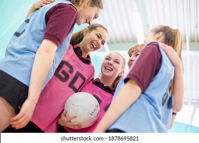 High School Volleyball Players Laughing While Hugging Each Other In A Huddle.