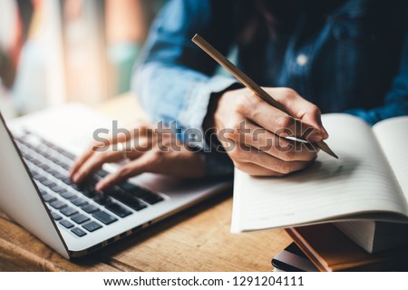 high school,college,university student using typing laptop searching information from network.people writing on notebook in modern library concept for scholarship to research international education l