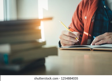 high school,college,university student writing in class room or library at work space with book stack for knowledge prepare exams scholarship study abroad.research world international education learn