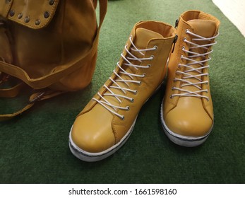 High shoes for men. Walking boots with white shoe laces. Modern fashion of men's casual footwear and unisex leather rucksack viewed in home hallway. - Shutterstock ID 1661598160
