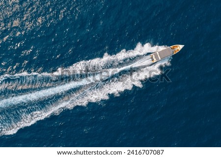 High speed boat rushing along the water surface of warm tropical waters, transfer of tourists. Aerial top view above.