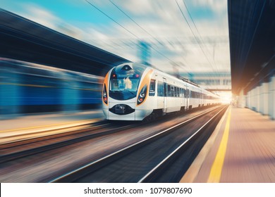 High Speed Passenger Train In Motion On The Railway Station At Sunset In Europe. Modern Intercity Train On Railway Platform With Motion Blur Effect. Urban Scene With Railroad. Railway Transportation