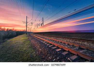 High Speed Passenger Train In Motion On Railroad At Sunset. Blurred Modern Commuter Train. Railway Station And Colorful Sky. Railroad Travel, Railway Tourism. Industrial Landscape. Transportation