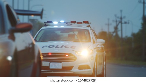 High Speed Police Pursuit On Highway. View Of Cop Patrol Car Chasing A Thief On Red Modern Car Driving Away From The Law.