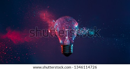 High speed studio photography, moment of the impact of a bullet on a classic electric bulb. Detail of glass explosion, blue and purple lighting. Concept of obsolete energy.