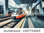 High speed train in motion inside modern train station in Vienna. Fast red intercity passenger train with motion blur effect. Railway platform. Railroad in Europe. Commercial transportation. Transport
