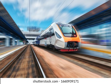 High Speed Train In Motion On The Railway Station At Sunset. Modern Intercity Passenger Train With Motion Blur Effect On The Railway Platform. Industrial. Railroad In Europe. Commercial Transportation