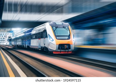 High speed train in motion on the railway station at sunset. Modern intercity passenger train with motion blur effect on the railway platform. Industrial. Railroad in Europe. Transportation. Industry