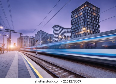 High speed train in motion on the railway station at sunset. Moving blue modern intercity passenger train, railway platform, buildings, city lights. Railroad in Vienna, Austria. Railway transportation