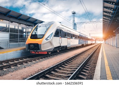 High speed train the railway station at sunset  Industrial landscape and modern intercity passenger train the railway platform   blue cloudy sky  Railroad in Europe  Commercial transportation