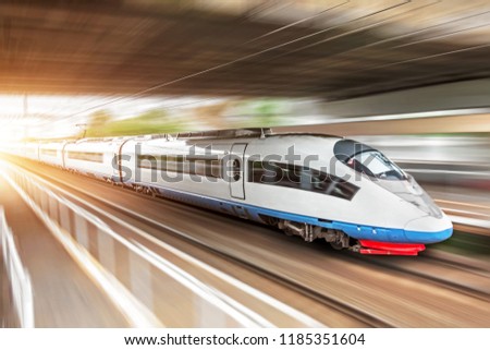 High speed train rides at high speed at the railway station in the city, through a tunnel under a bridge