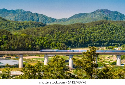 High speed train speeding across concrete railroad bridge in rural countryside.  - Powered by Shutterstock