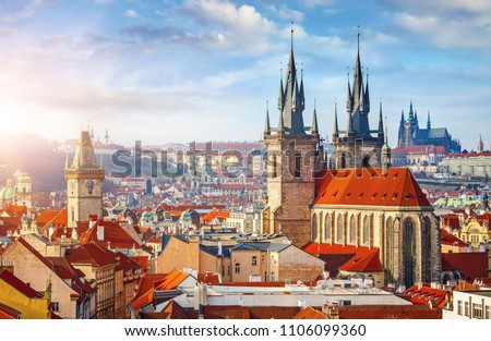 High spires towers of Tyn church in Prague city (Church of Our Lady before Tyn cathedral) urban landscape panorama with red roofs of houses in old town and blue sky with clouds.