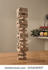 A high stack of Jenga blocks balancing precariously on a wooden table in a cozy setting.