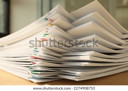 High stack of office documents with clips on office table close up. Concept of overworking and paperwork in office.