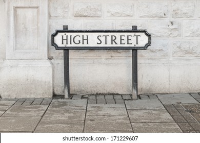A High Street road sign in front of a white wall