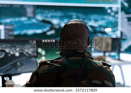 High tech officer processing real time data for important operations, gathering intelligence for field troops and coordinating strategic planning tactics. Command post defense tasks.
