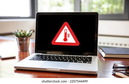 High temperature warning sign on a laptop screen.  Computer overheating concept. Heavy load and hot weather danger. Business office desk background.
