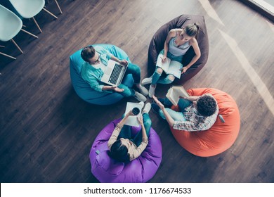 High top angle view of diversity stylish and modern hipster youngster sit in colorful armchairs on the wooden floor work together on the task sit classmates chair bag - Powered by Shutterstock