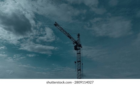 High tower crane against a dramatic overcast sky with teal and moody color grading.