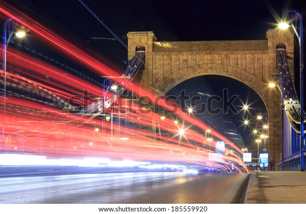 High traffic lights on ancient bridge with\
city lights all in the middle of the\
action